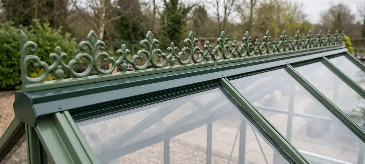 Ornamental ridge cresting in a single moss green colour on a glass greenhouse roofline