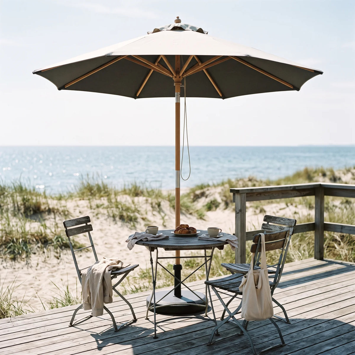 Venedig Parasol Ø1.8 m in Grey over a bistro table on a seaside deck