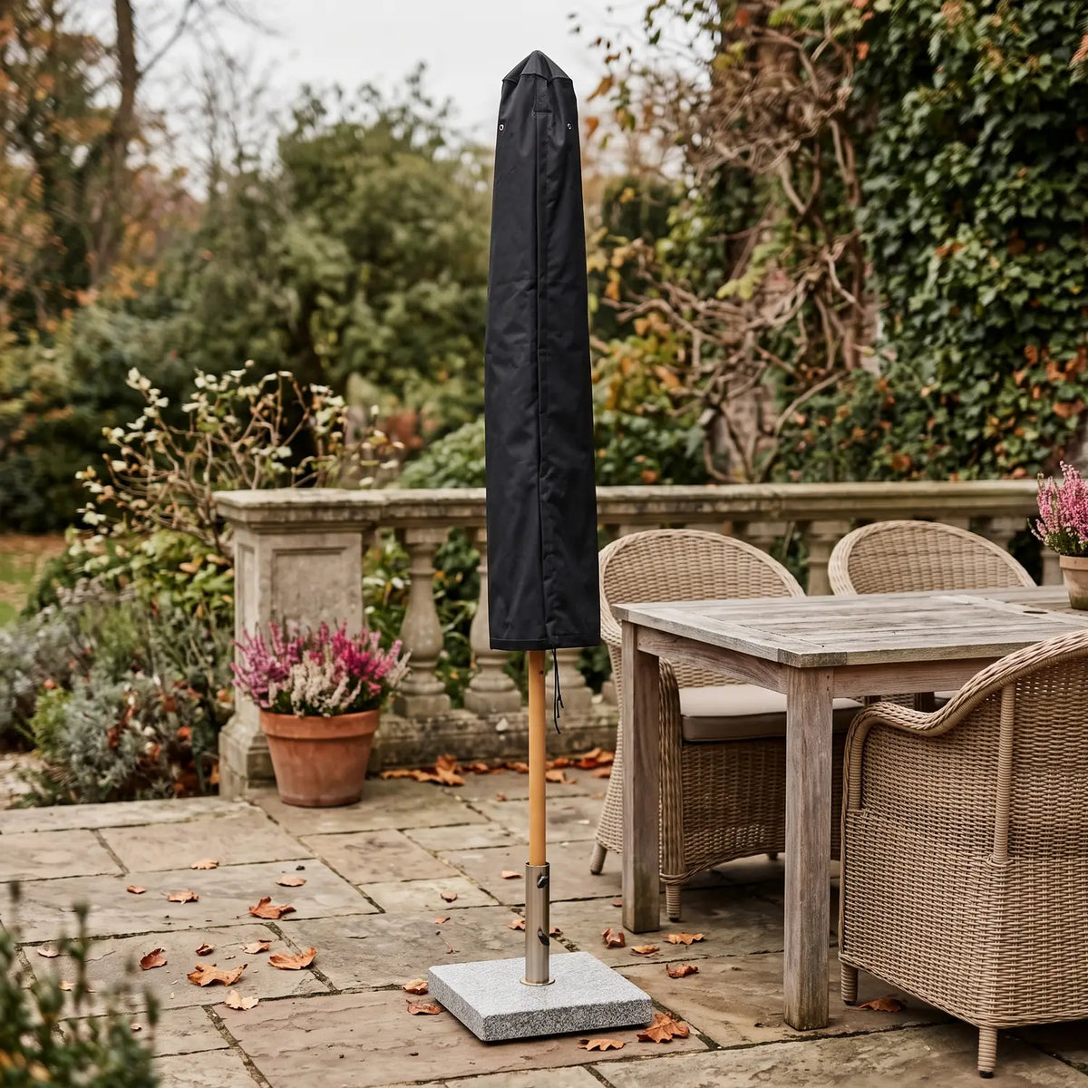 Parasol Cover 140 cm in black over a folded parasol on a garden terrace in autumn